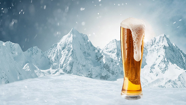 Winter vacations. Big glass of light cold foamy beer over snow-capped mountains background. Holidays, vacation, drinks, taste, ad and Beer Fest concept. Design for wallpaper, greeting card